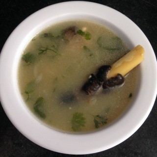 paya soup served in a bowl and a leg piece appearing on top of the soup