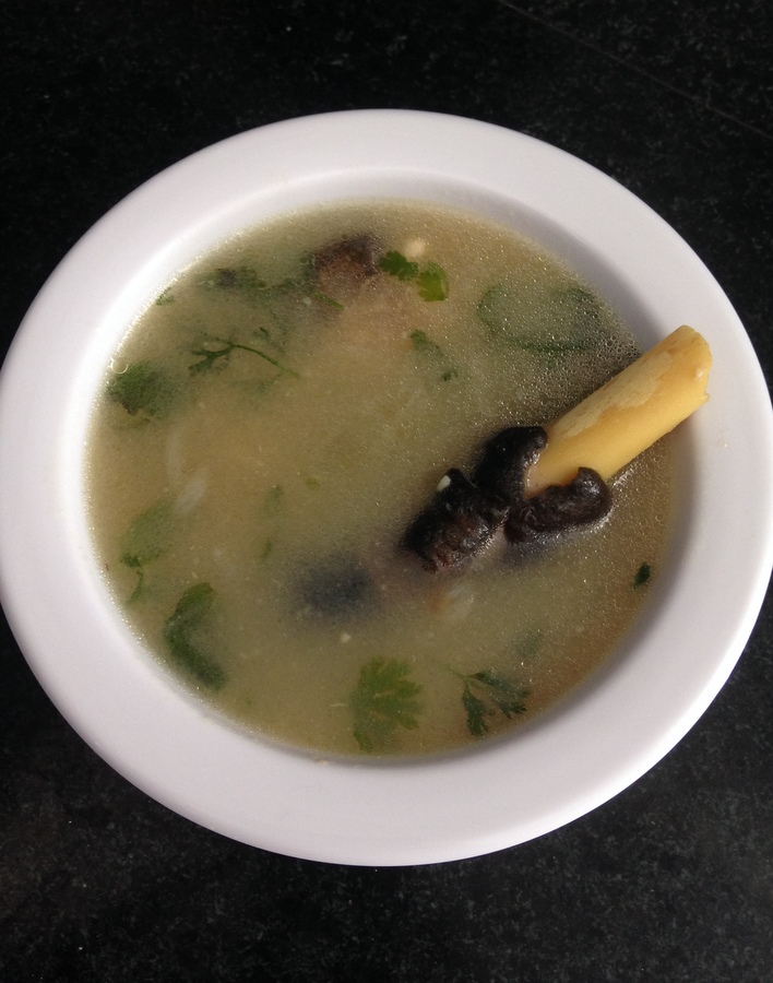 paya soup served in a bowl and a leg piece appearing on top of the soup
