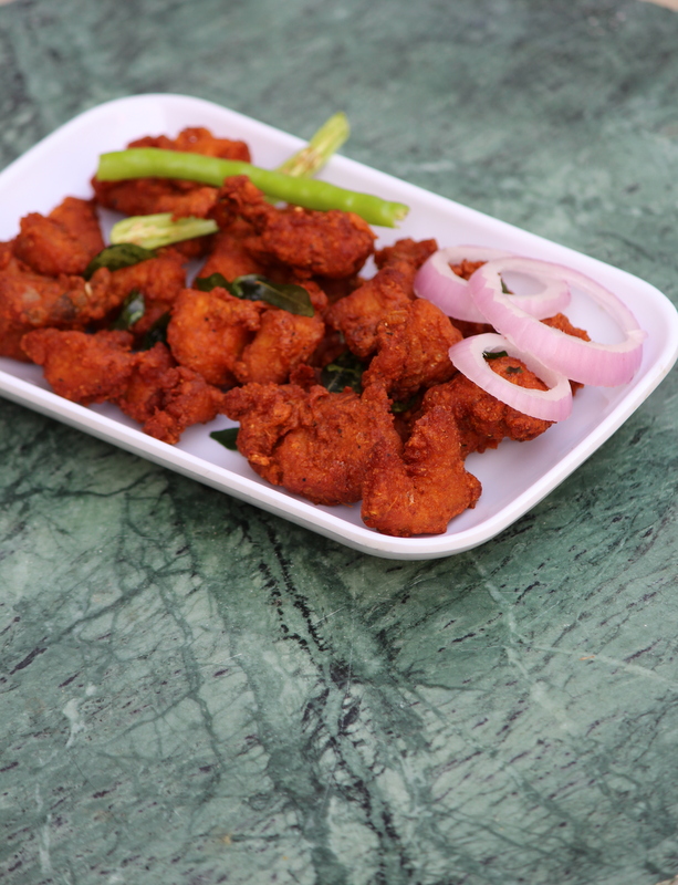 deep fried pakora served on a plate with onions and chilli topping
