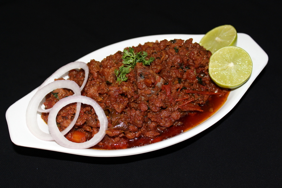 mutton keema in a bowl with garnished onion rings