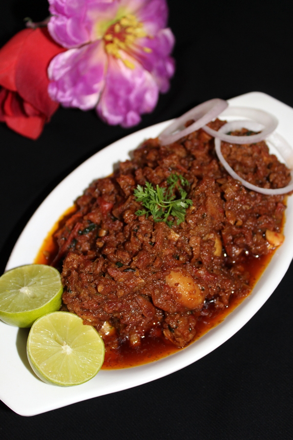 mutton keema in a bowl with garnished onion rings