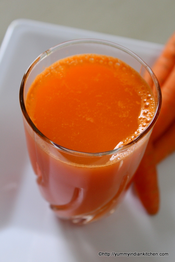 serving carrot juice in a glass with some carrots on a plate