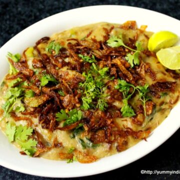 haleem served in a bowl with onions, mint leaves and lemon spread as garnishing over it