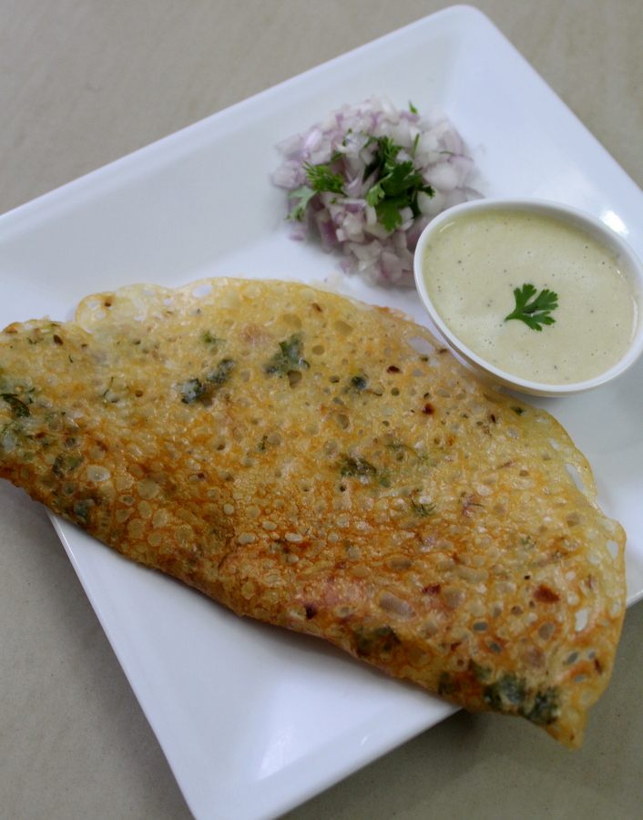 crispy rava dosa on a plate with chutney in a small bowl