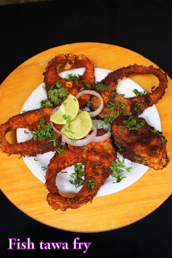 fish fry masala on a plate with onion rings, lemon wedges, coriander leaves