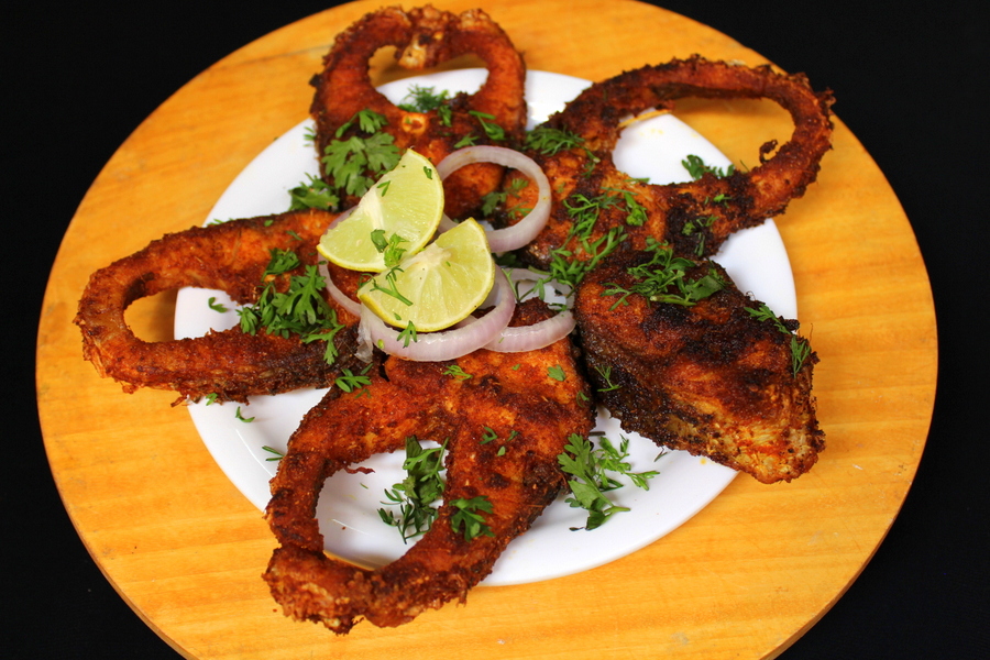 fish fry on a plate with onion rings, lemon wedges, coriander leaves