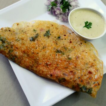 rava dosa on a plate with chutney in a small bowl