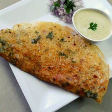 rava dosa on a plate with chutney in a small bowl