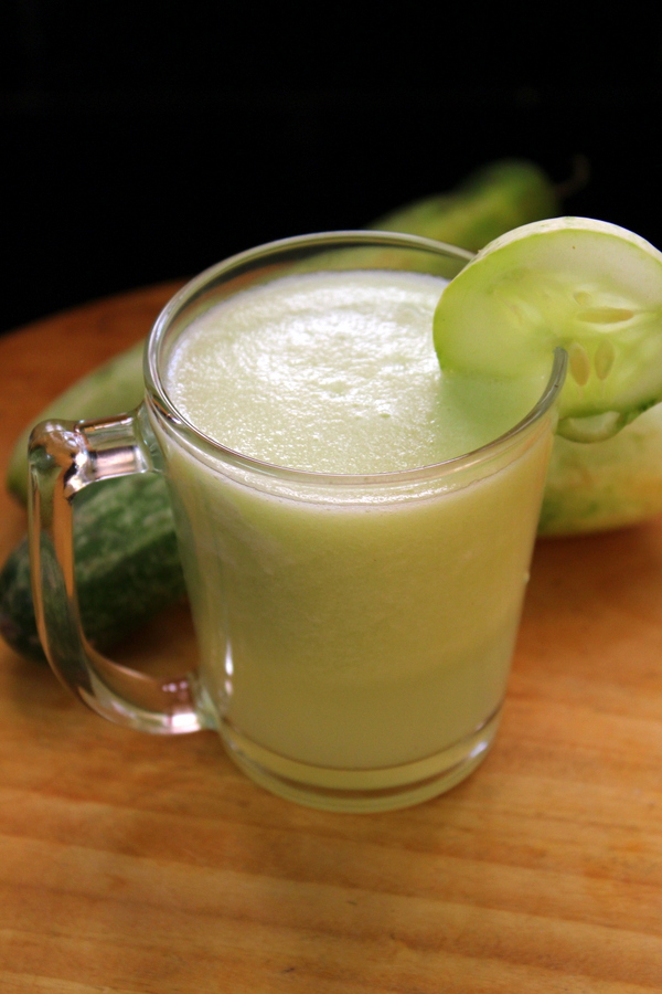 cucumber juice in a glass with a cucumber slice to the glass