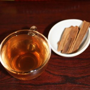 cinnamon water in a cup with cinnamon sticks in a small bowl