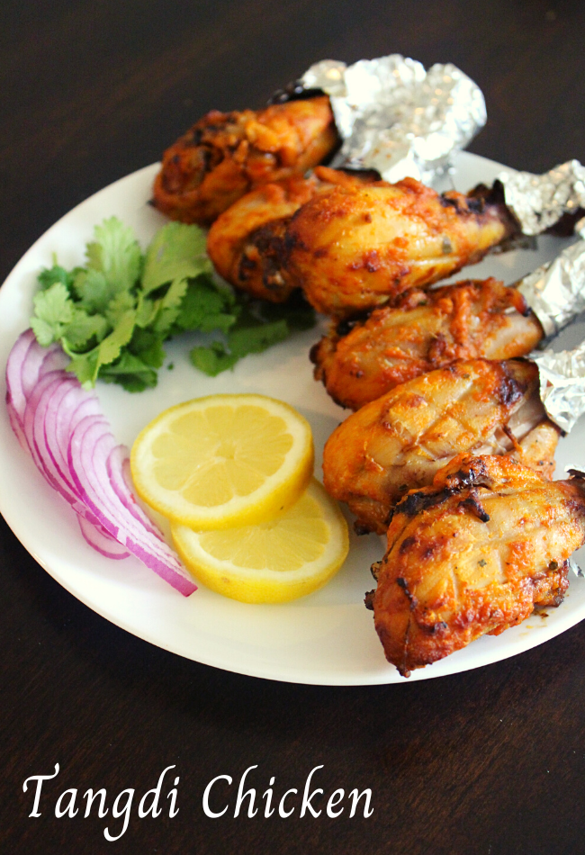 tangdi chicken on a plate with lemon slices and onions