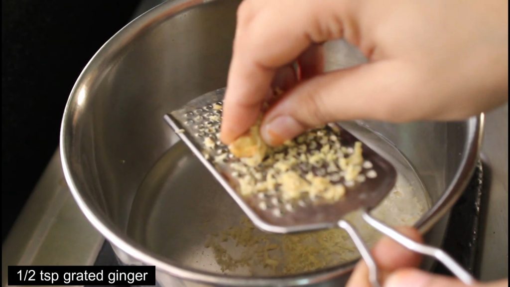 grating ginger into the water in the pan