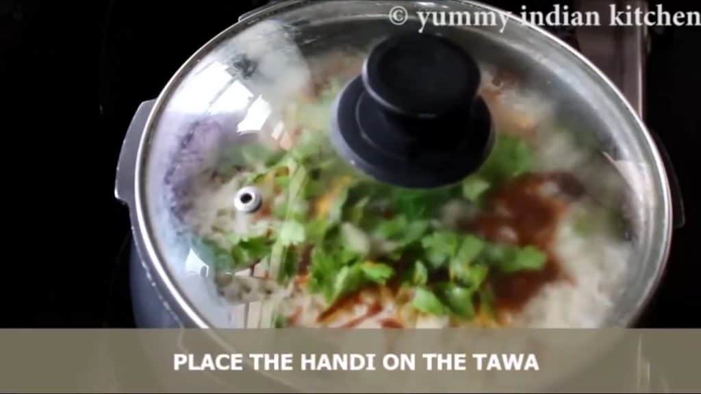 Placing the handi on the tawa to make chicken biryani recipe