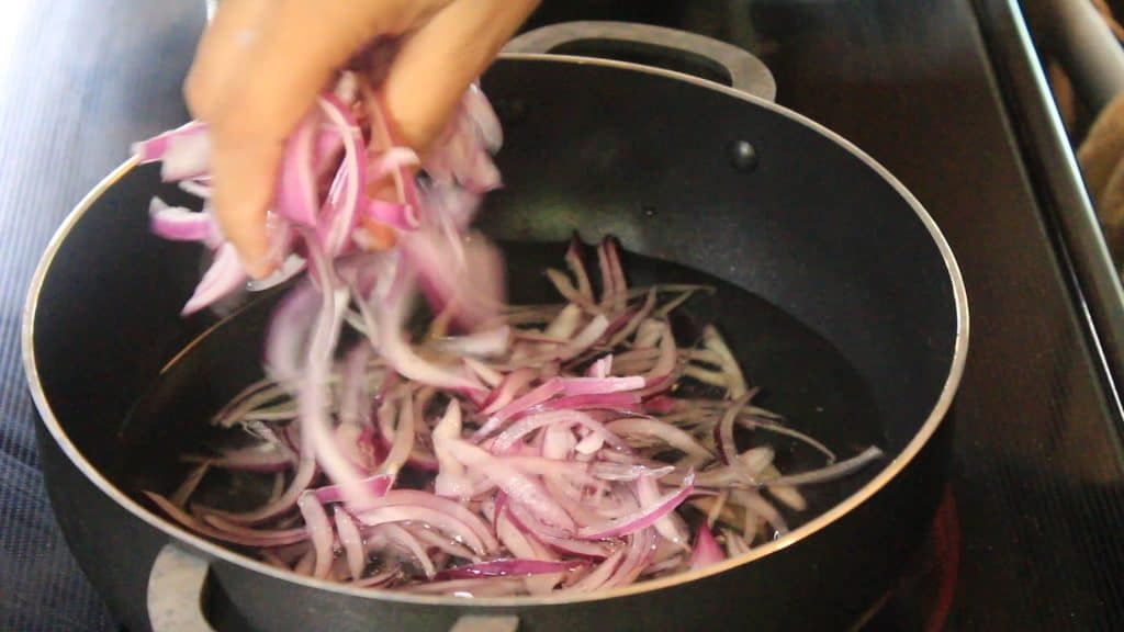 adding the sliced onions into the hot oil carefully