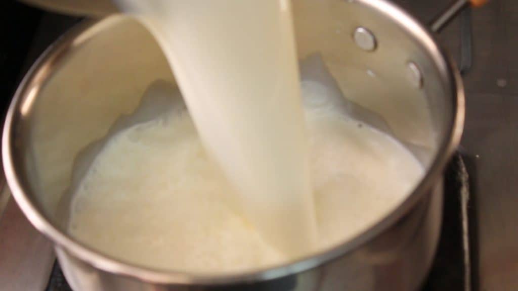 taking a cooking pot and pouring the milk