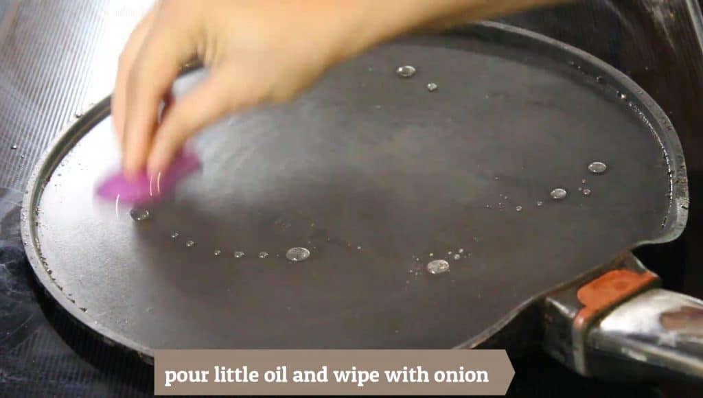 Brush oil or an onion slice on the non stick tawa