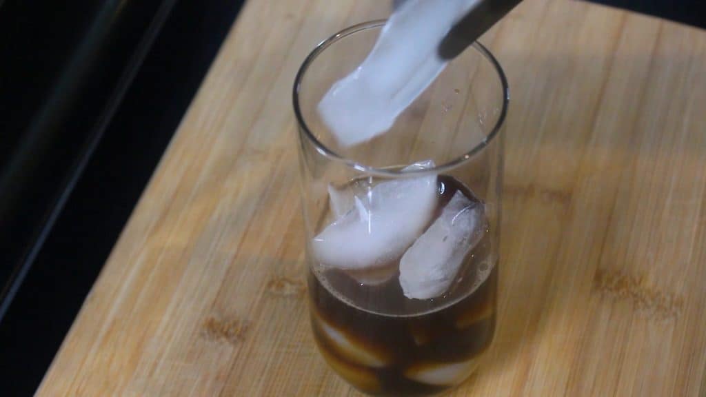 adding some ice cubes into the glass
