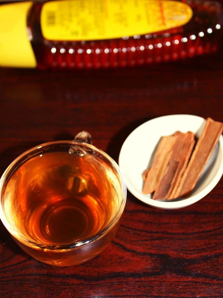 cinnamon drink in small cup with cinnamon sticks placed beside in a small bowl