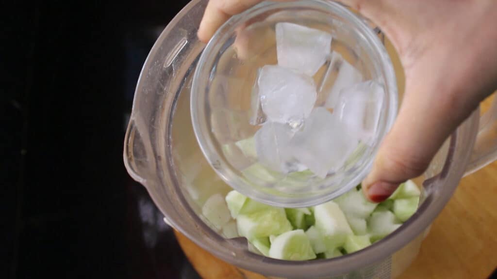 adding some ice cubes to the cucumber juice