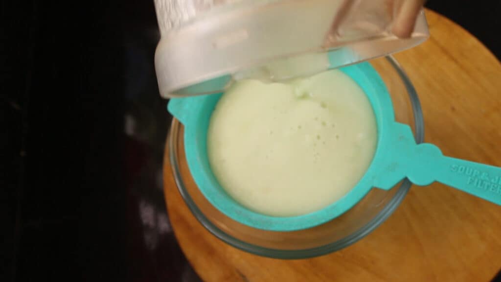 straining blended juice in a bowl