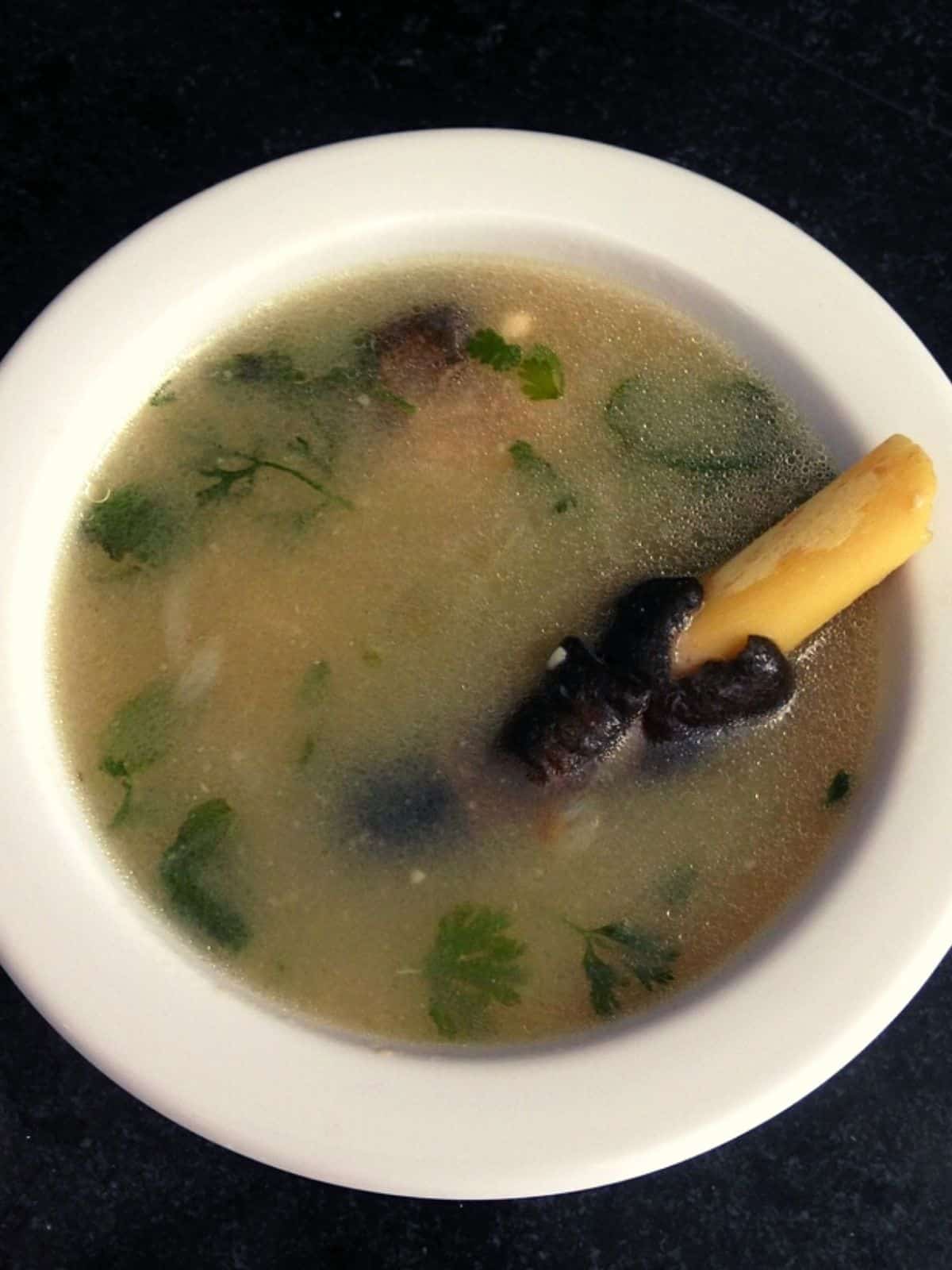 paya soup in a serving bowl with goat leg in the soup