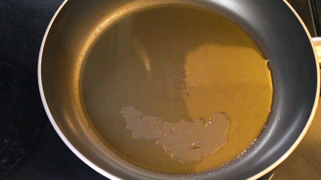 Adding oil into a pan and heating it