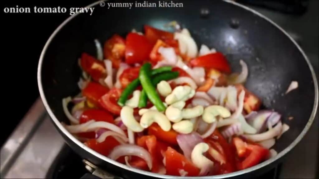 Adding the sliced onions and chopped tomatoes, green chilies, cashew nuts