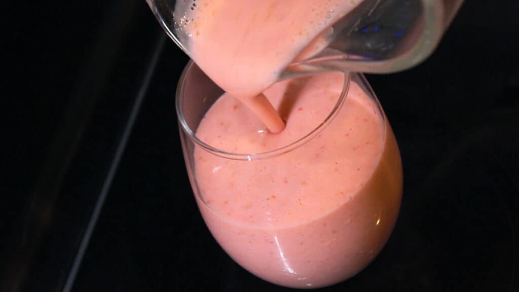 Pouring the Mcdonald's Strawberry Banana Smoothie with yogurt