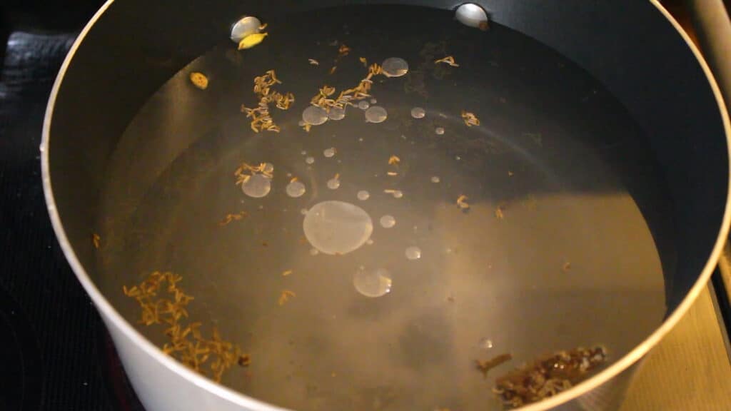 Adding enough water, salt as per taste,  cloves, cardamoms, cinnamon, shahi zeera, a teaspoon of oil and lemon extract