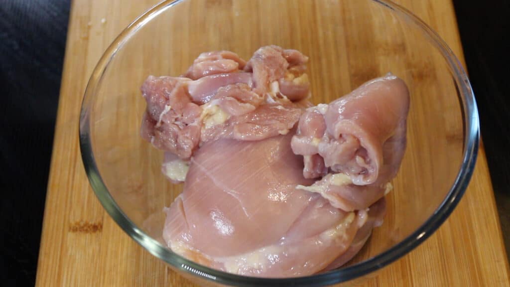 Adding the boneless and skinless chicken thighs to a mixing bowl
