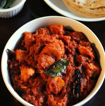 achari chicken served in a bowl with chapati beside