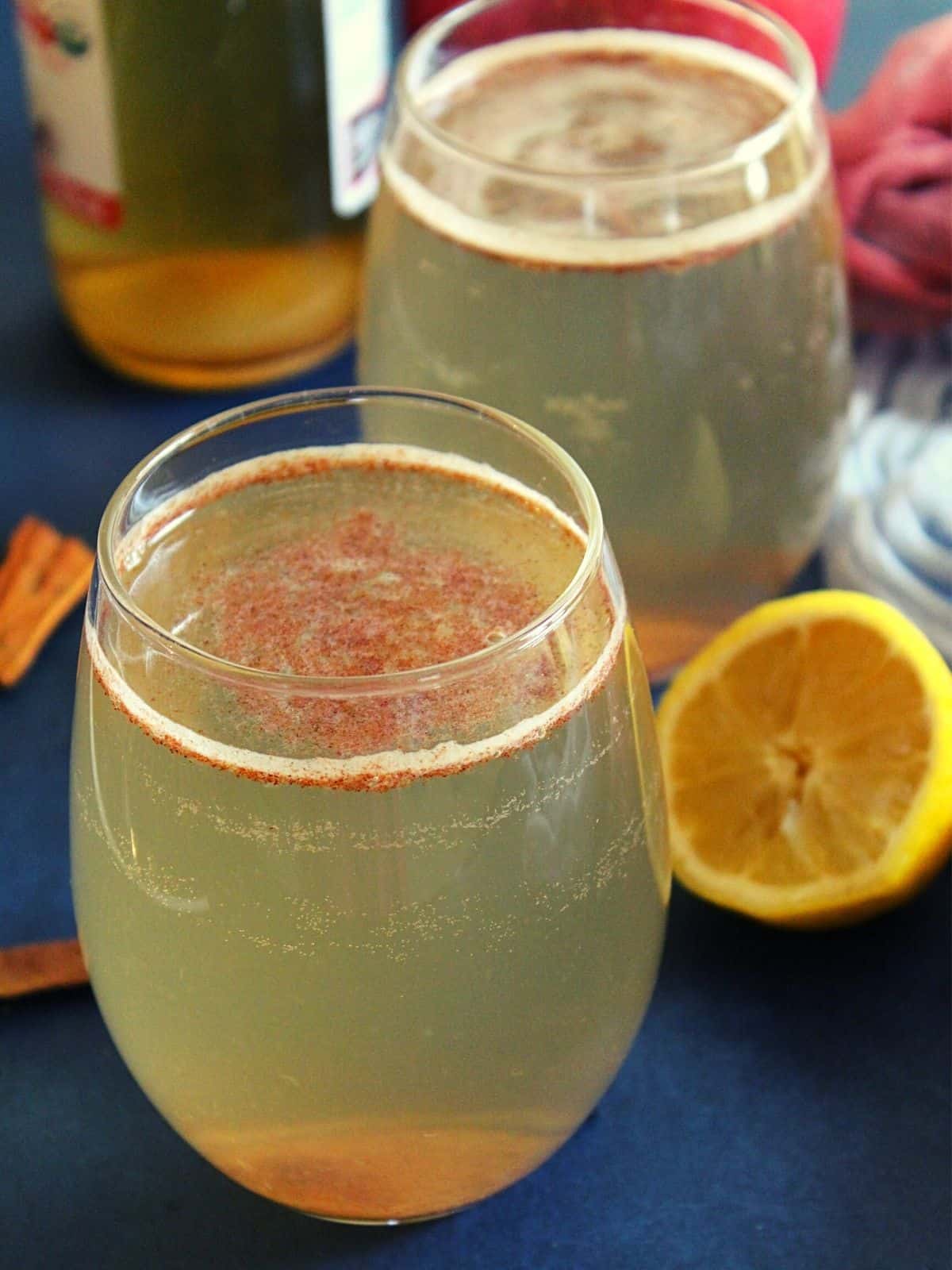 apple cider vinegar and honey drink with cinnamon is served in a glass with lemon