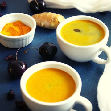 turmeric coffee served in 2 cups with ginger placed beside