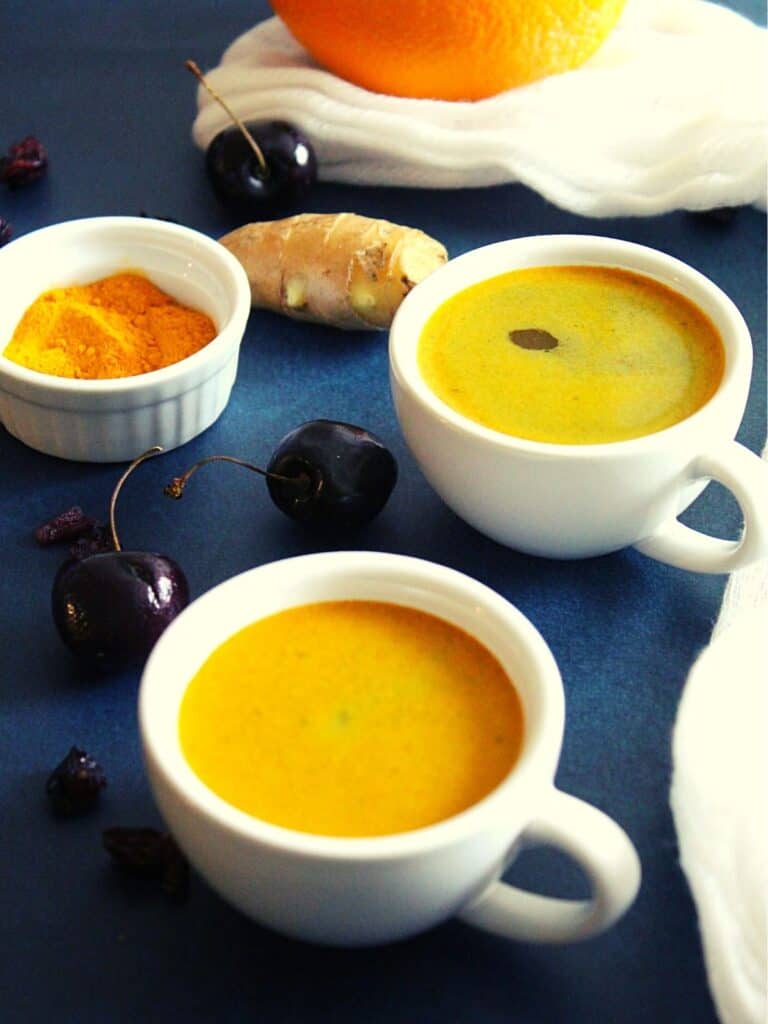 turmeric coffee served in 2 cups with ginger placed beside