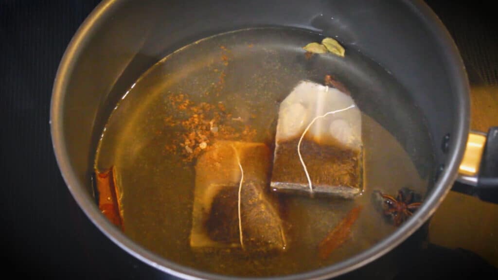 adding whole spices and tea bags to the chai tea concentrate