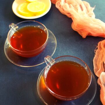 black tea for weight loss served in two cups with round lemon slices as garnishing on a small plate