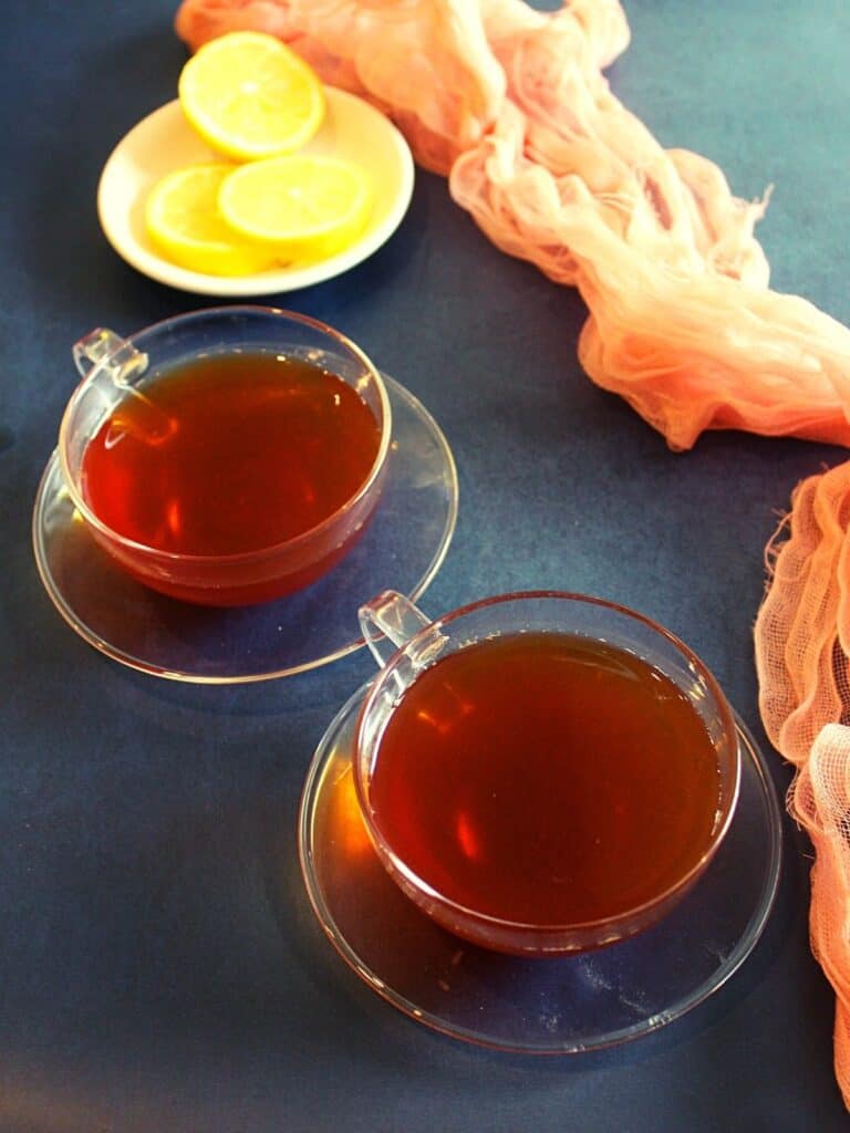 black tea for weight loss served in two cups with round lemon slices as garnishing on a small plate