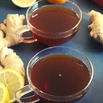 lemon and ginger tea served in a cup with ginger and lemon garnishing