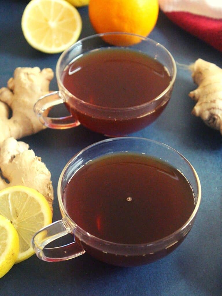 lemon and ginger tea served in a cup with ginger and lemon garnishing