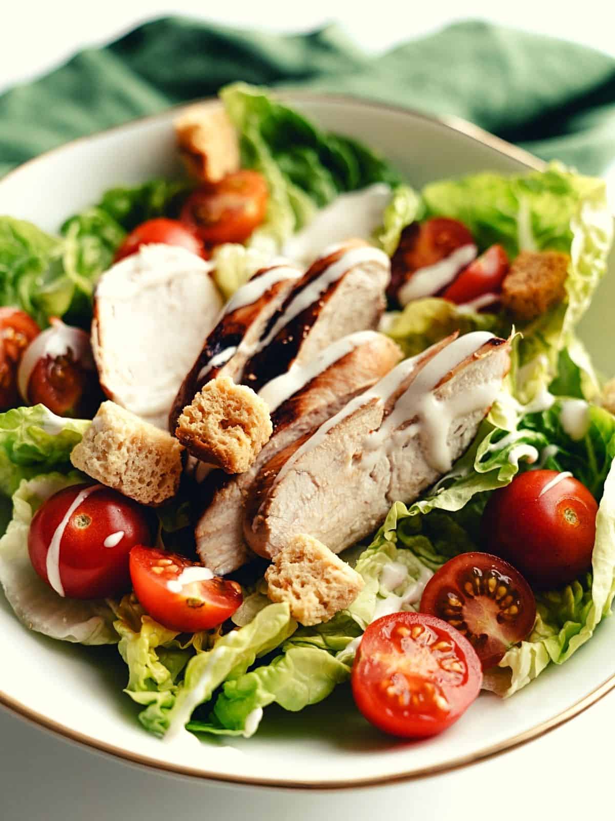 chicken salad in a bowl with baked chicken, veggies added to the bowl as chicken breast recipes to lose weight