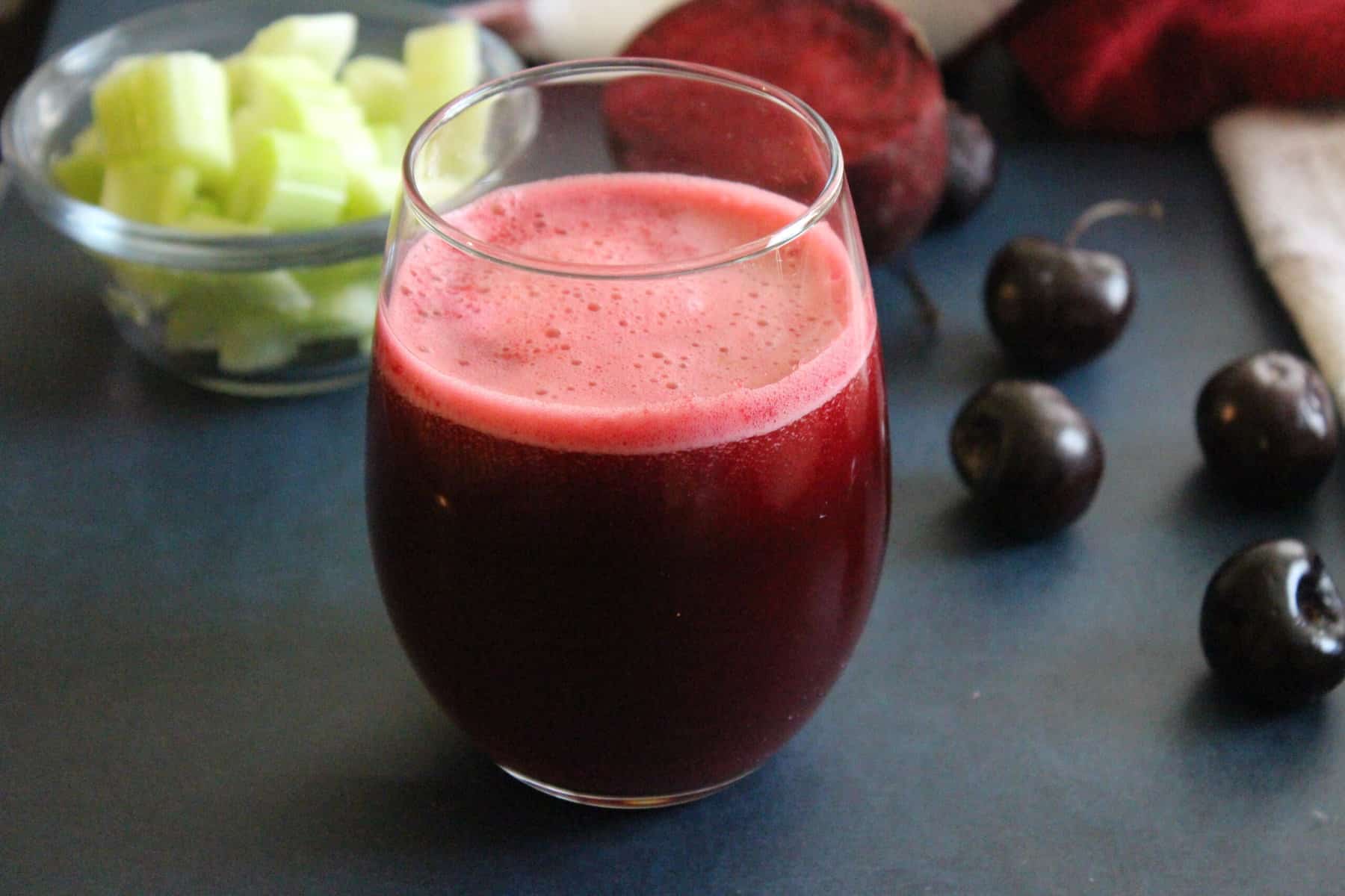 smoothie with beets and celery in a glass with berries aside