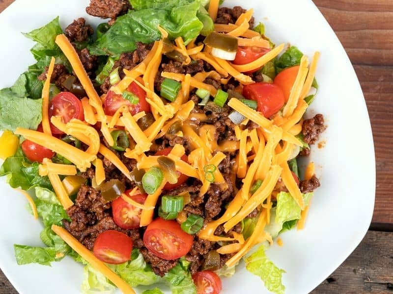 taco salad shown in a plate with turkey ground and veggies in it.