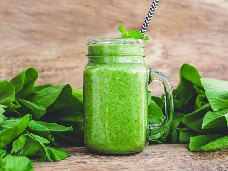 spinach detox in a mason jar with spinach placed beside as a detox smoothie