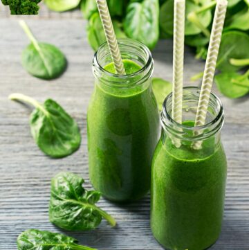 green smoothie for weight loss drink in two bottles with spinach and kale around