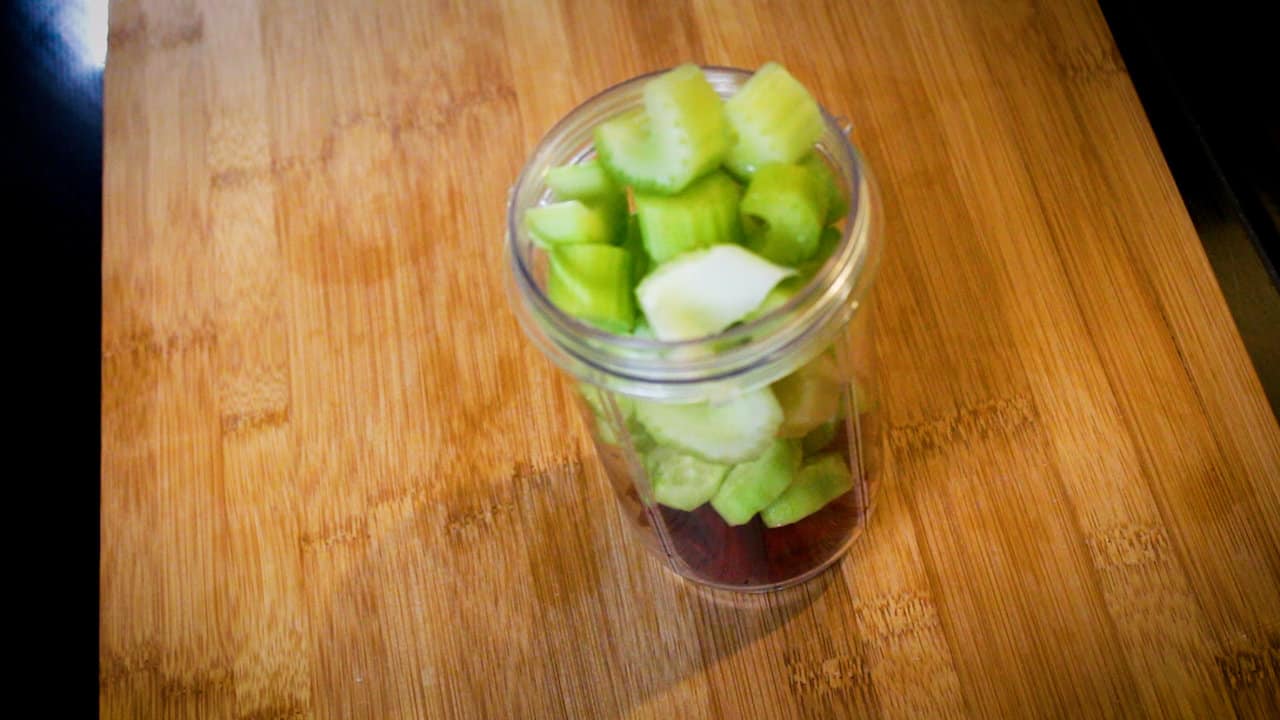 adding celery and ginger to jar with cucumbers