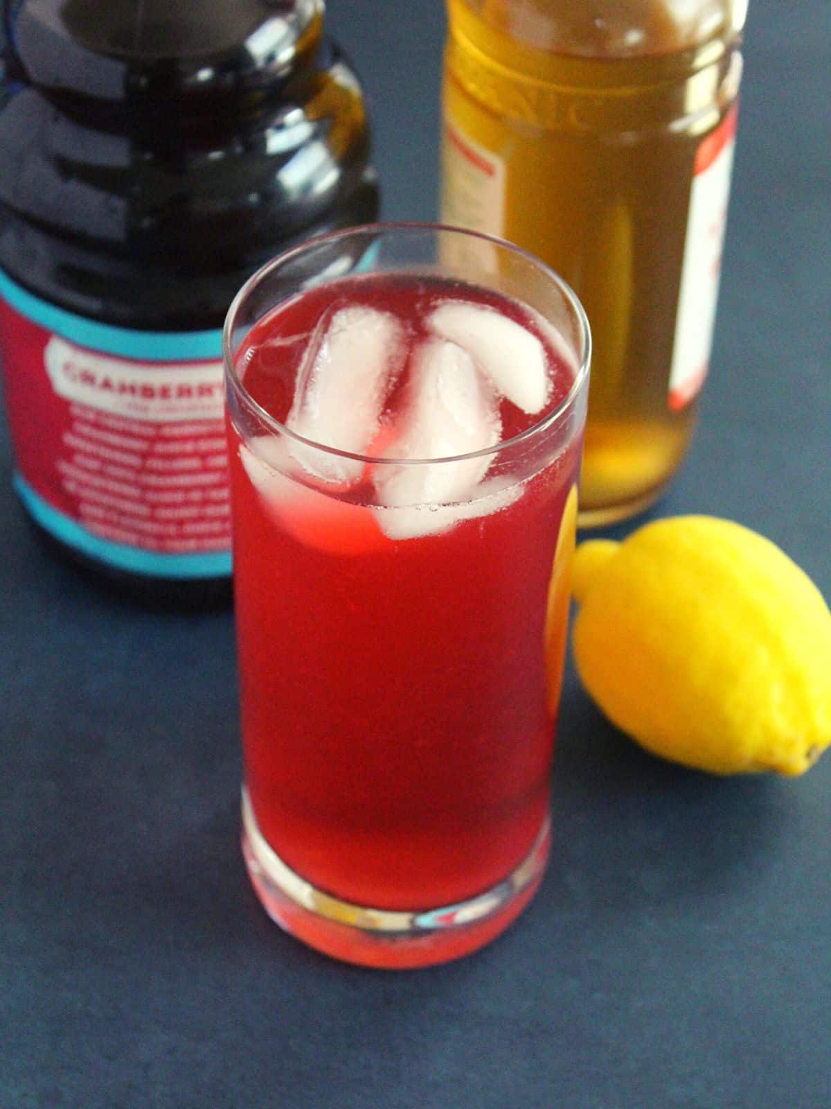 apple cider vinegar and cranberry juice drink in a glass with ice cubes in it