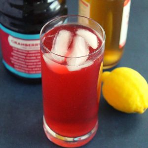 apple cider vinegar and cranberry juice detox drink in a glass with lemon beside