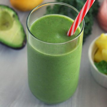 pineapple smoothie to lose weight in a glass with a straw by placing avocado, pineapple, kale beside