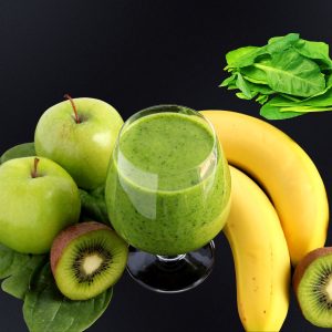 frozen spinach smoothie in a glass with banana kiwi apple and spinach around the glass