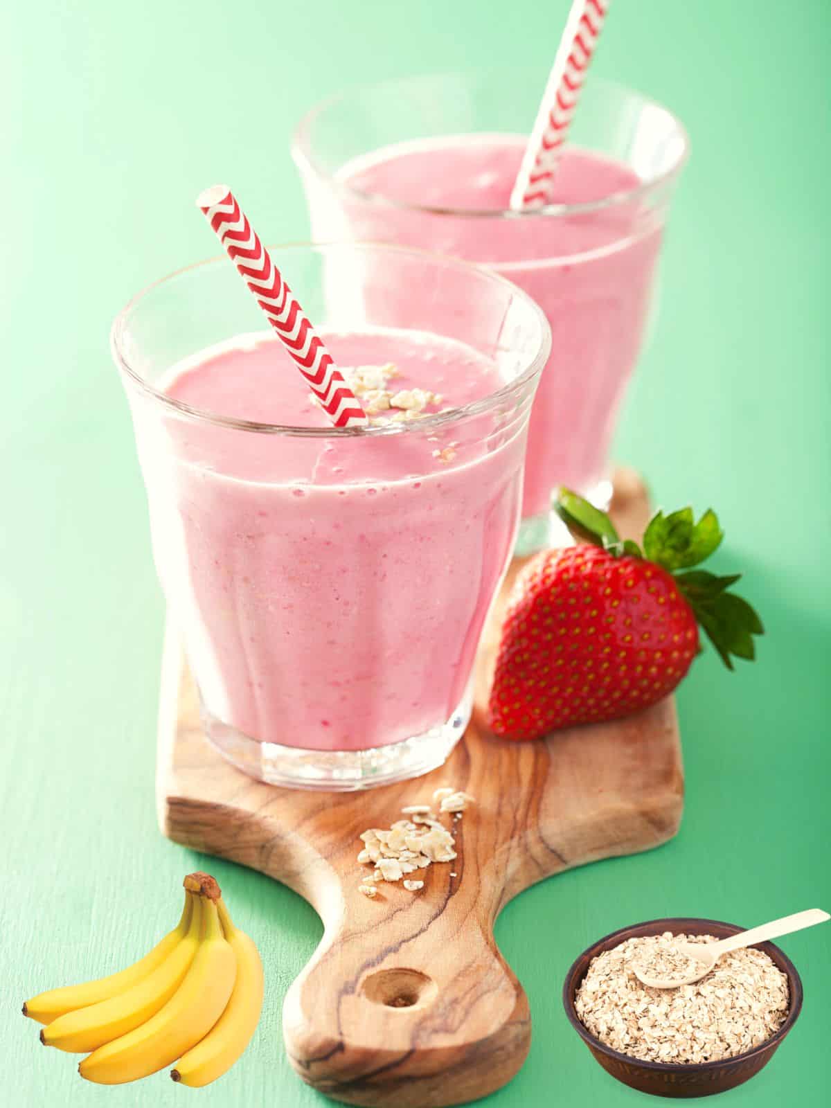 frozen strawberry smoothie on a wooden small board with strawberries, bananas and oats as garnishing 